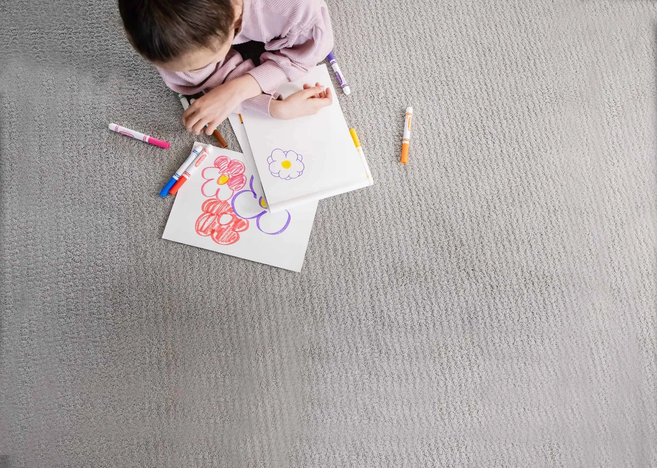Child coloring on clean carpet after professional stain removal